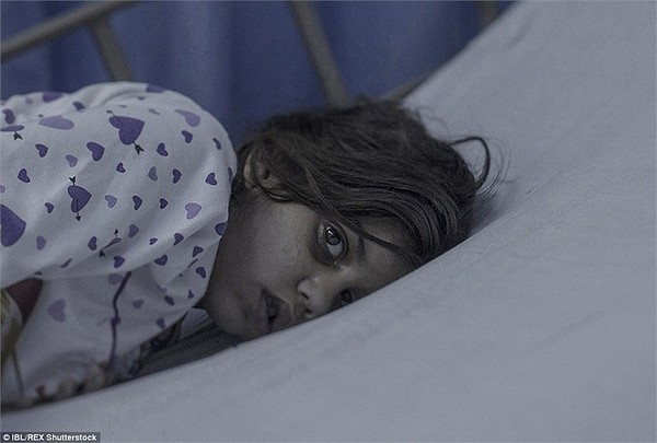 Bé Maram, 8 tuổi, ngủ trên một chiếc giường tạm bợ ở Amman, Jordan. Em vừa tỉnh dậy sau 11 ngày hôn mê vì đầu của em bị một mảnh tên lửa găm vào trong một vụ không kích. Đáng thương hơn, cơn xuất huyết não đã khiến em không thể nói được nữa.